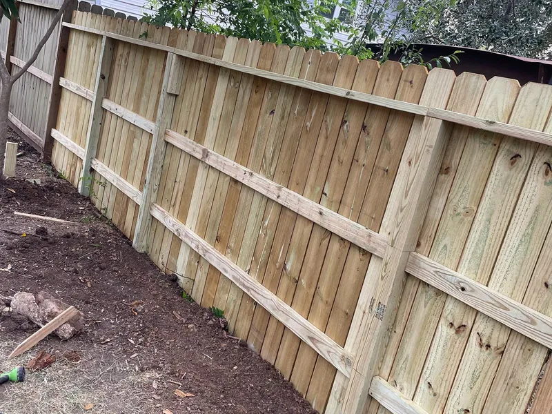 A new wood fence standing along the same line with fresh posts, rails and pickets