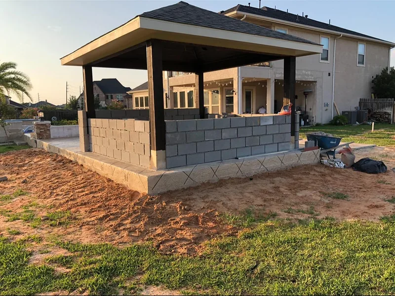 A pavilion under construction with bare block walls and dirt around the slab