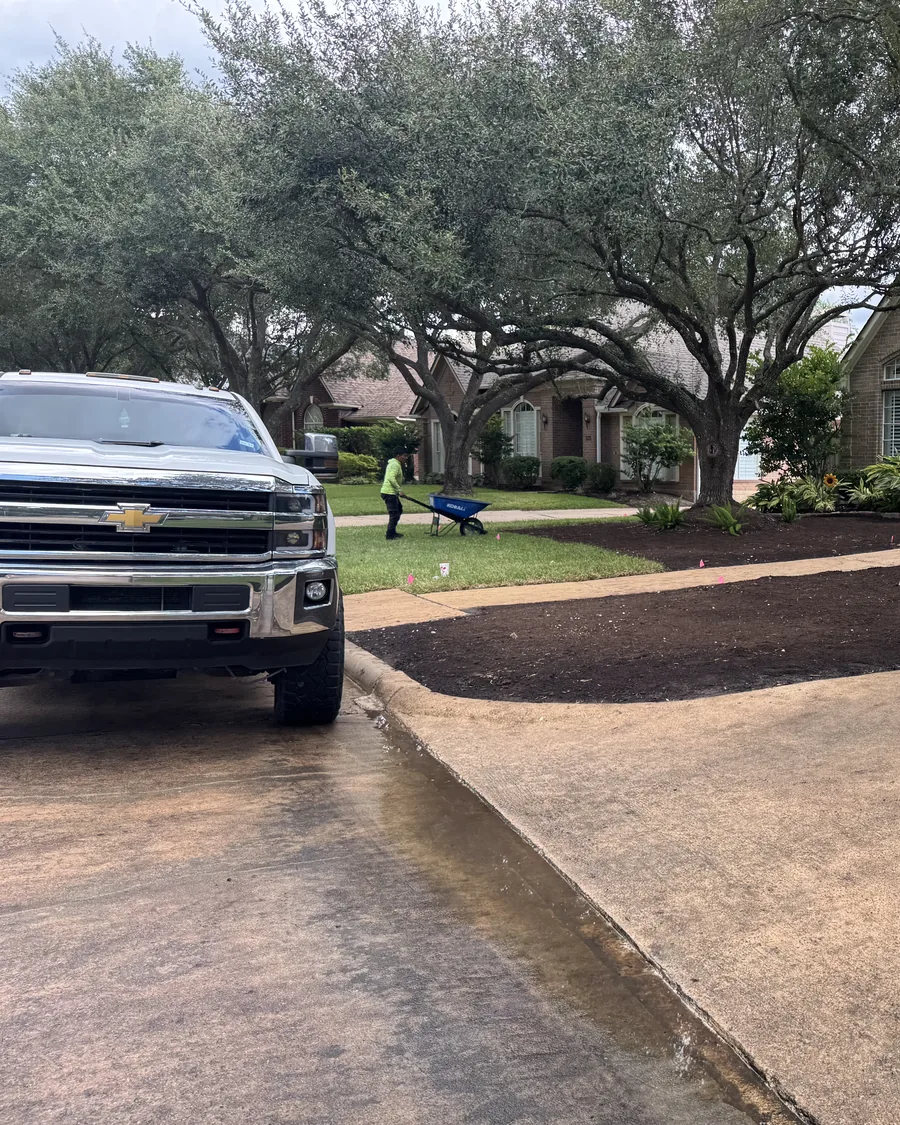 A pickup at the kerb with a crew member working on freshly mulched front beds