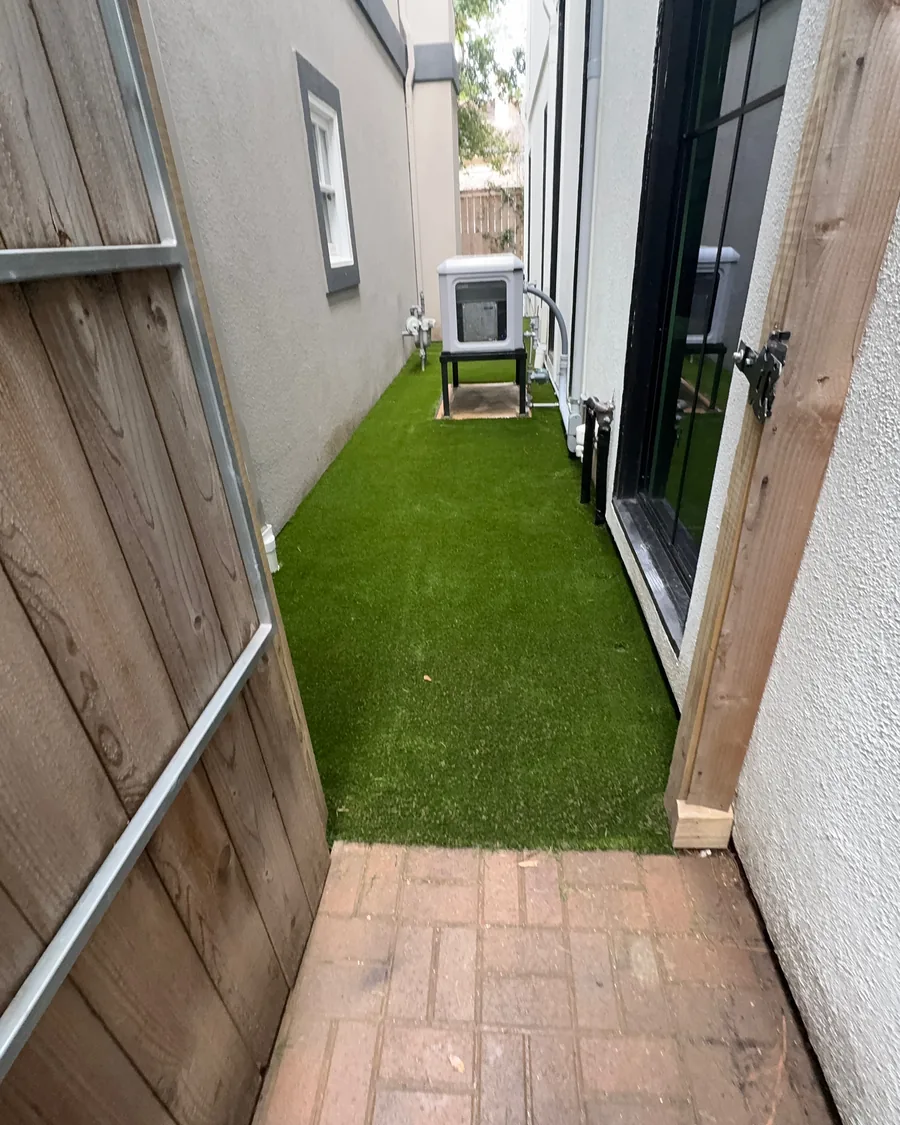 Artificial turf running between a fence and the house through a gate