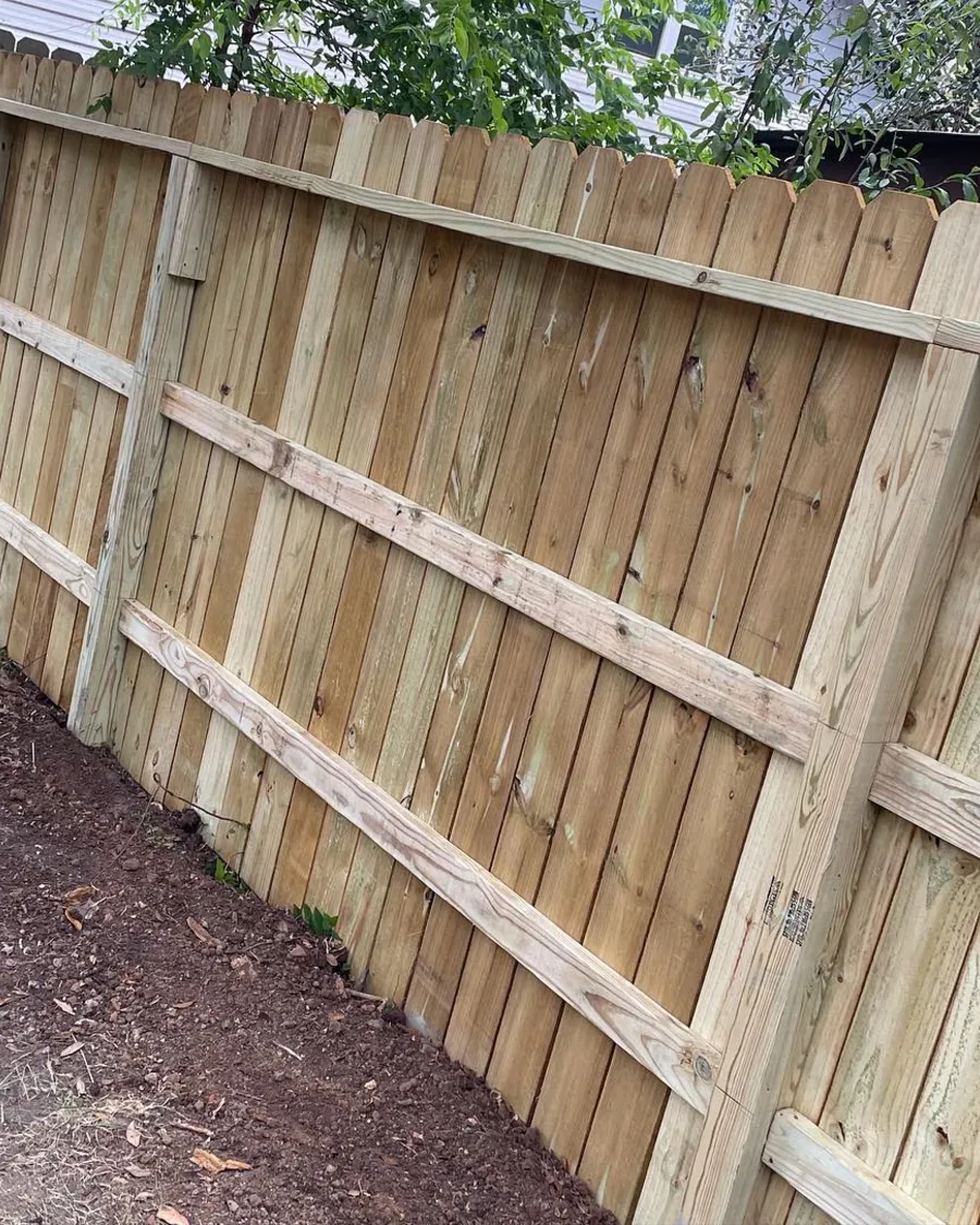 New wood fence with fresh rails and pickets along a back line