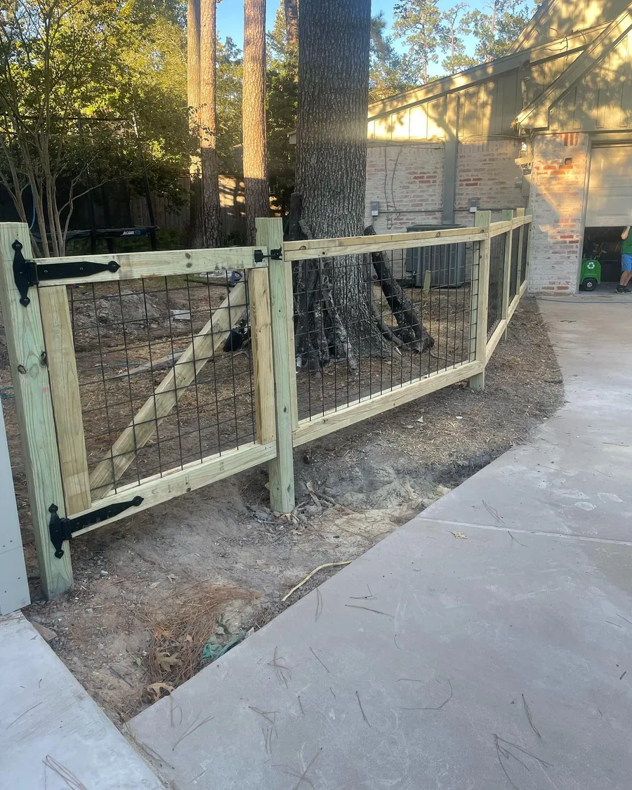 Custom wood and wire gate set on a concrete drive beside a mature tree