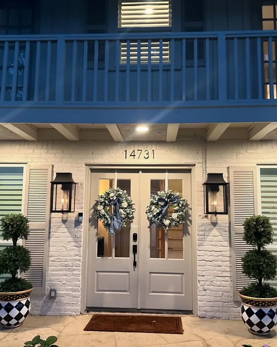 Front entry lit at night with lanterns and topiaries in planters
