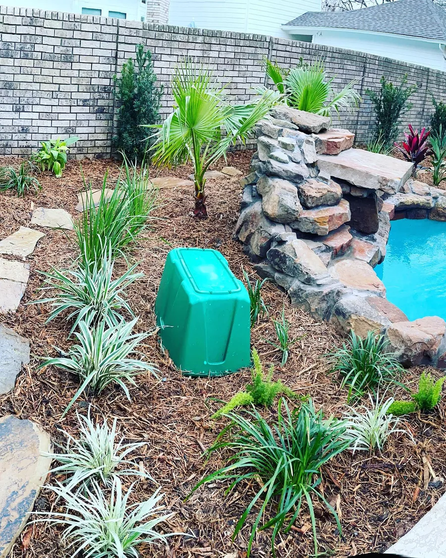 Stacked stone water feature beside a pool with tropical planting