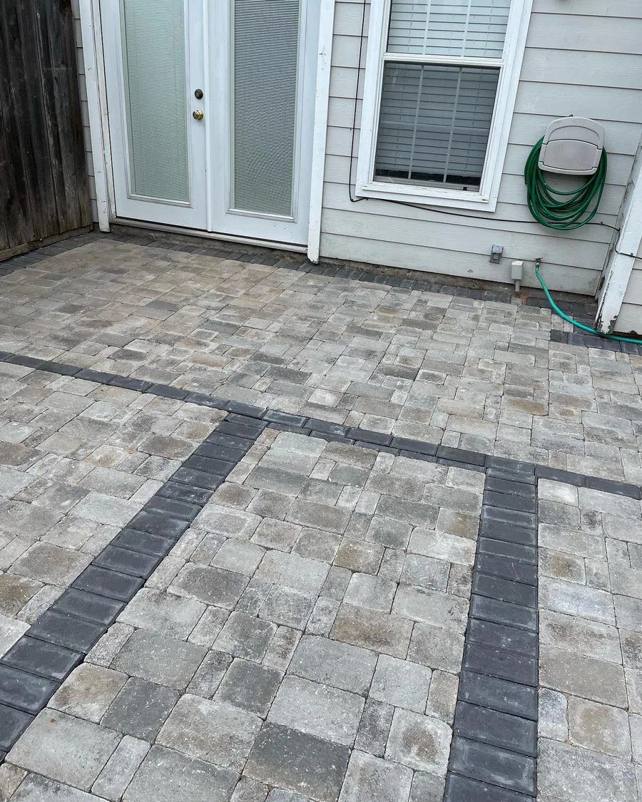 Paver patio laid with a contrasting dark border band running to the back door