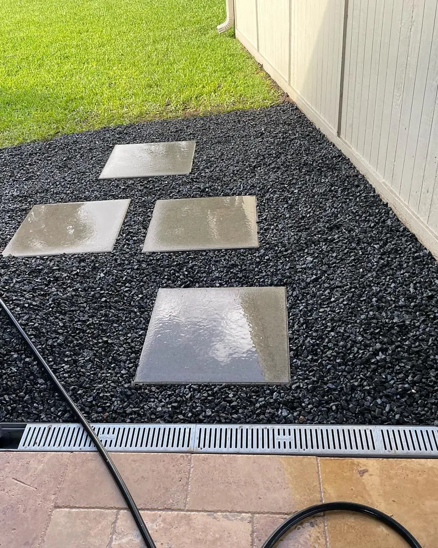 Flagstone squares set in black river rock with a drain