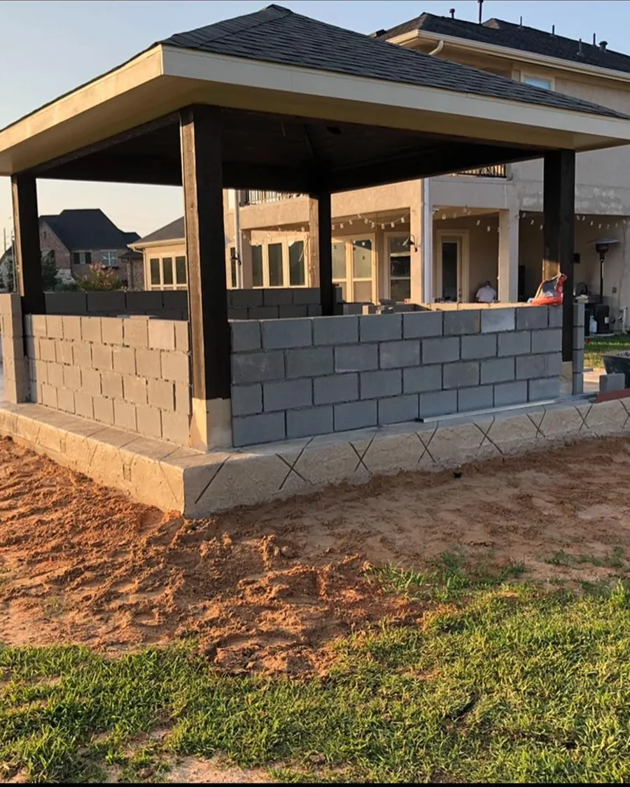 A pavilion under construction with block walls and posts up