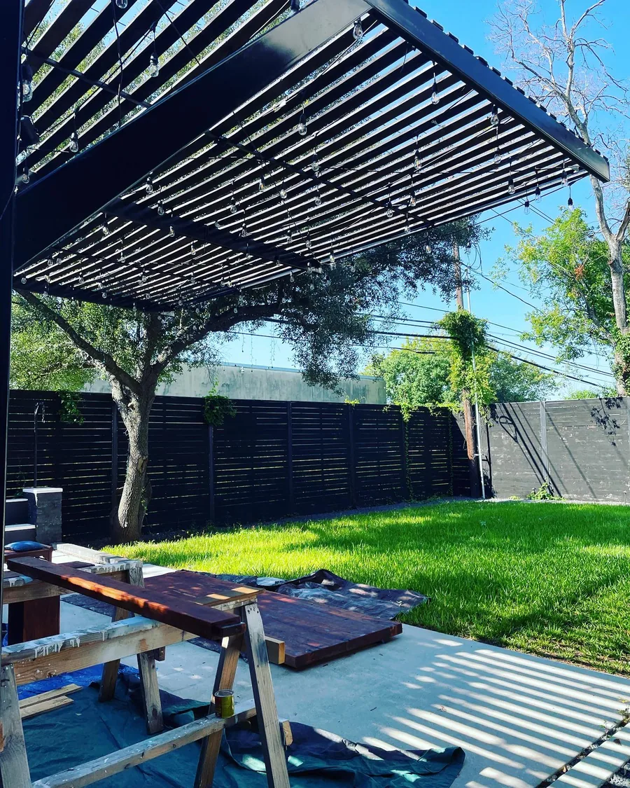 A black steel pergola over a bright turf lawn