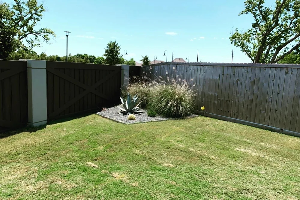 A clean, even lawn surface bordered by a wood fence