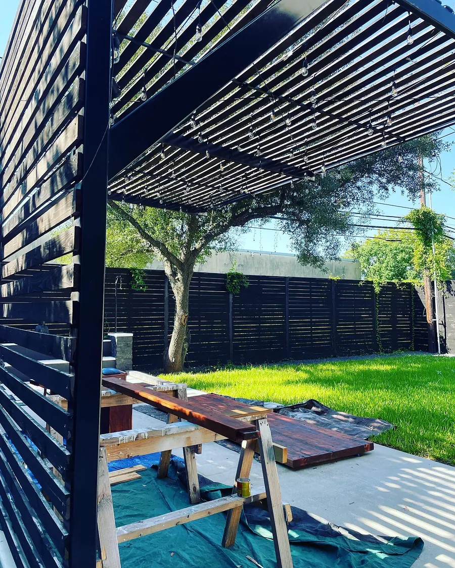 Bright artificial turf lawn under a black steel pergola